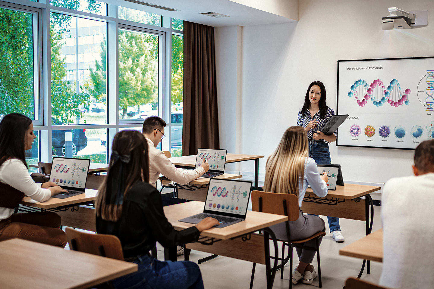 Un profesor y sus alumnos utilizan computadoras Galaxy Book en clase para aprender.